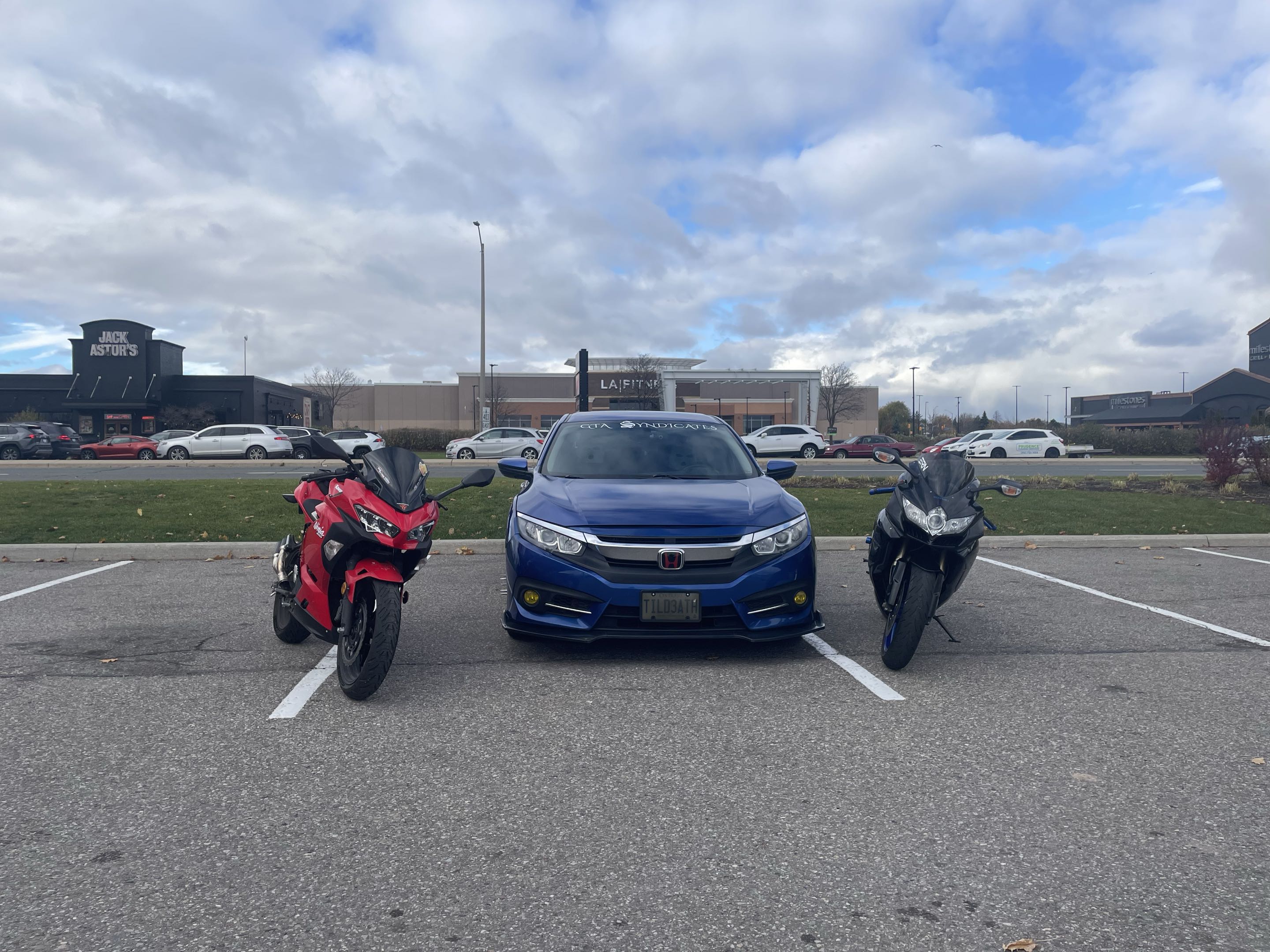 Red Ninja, blue Honda Civic, and black bike lined up in parking lot