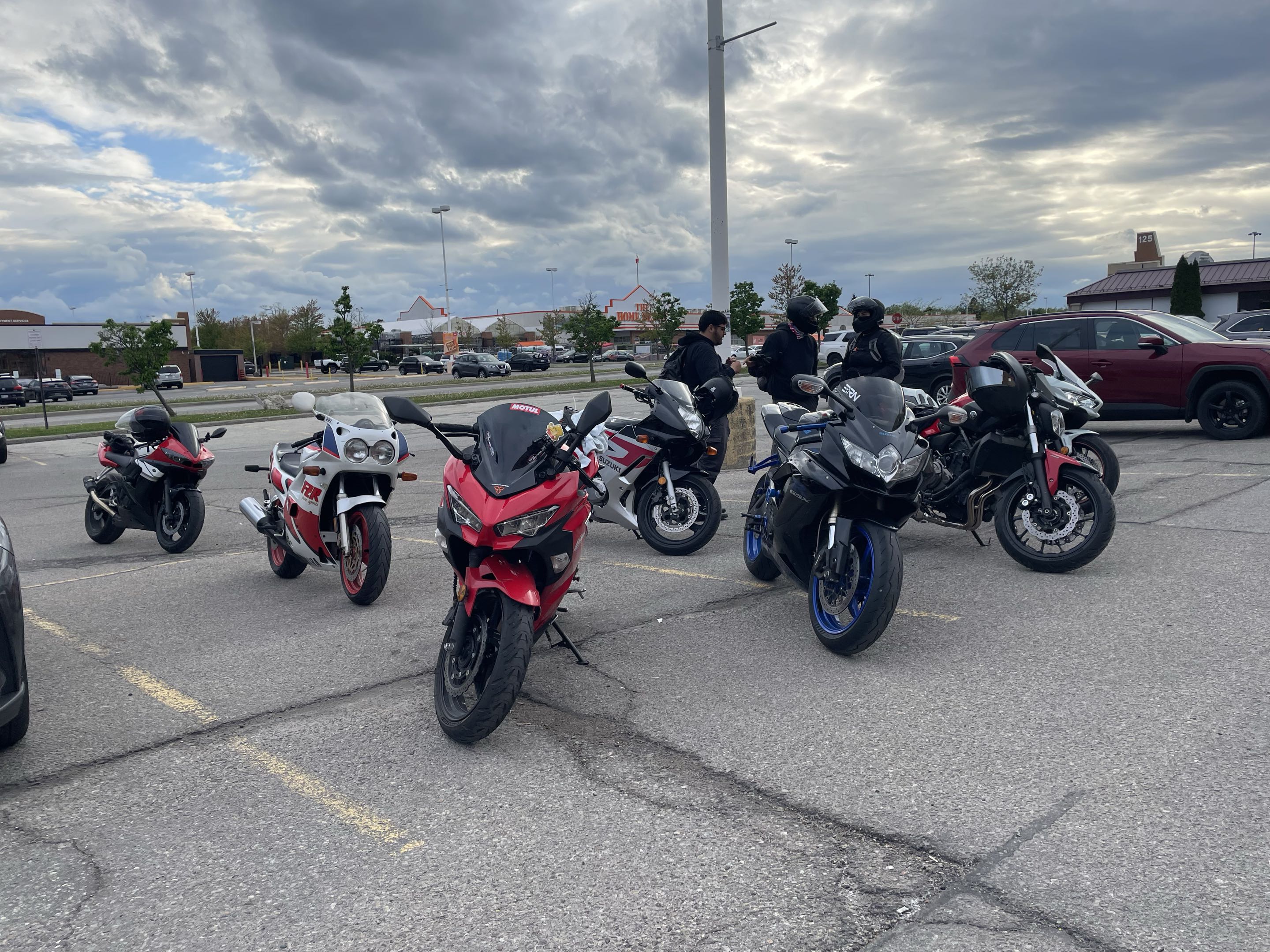 Group of bikes with riders gathering in parking lot