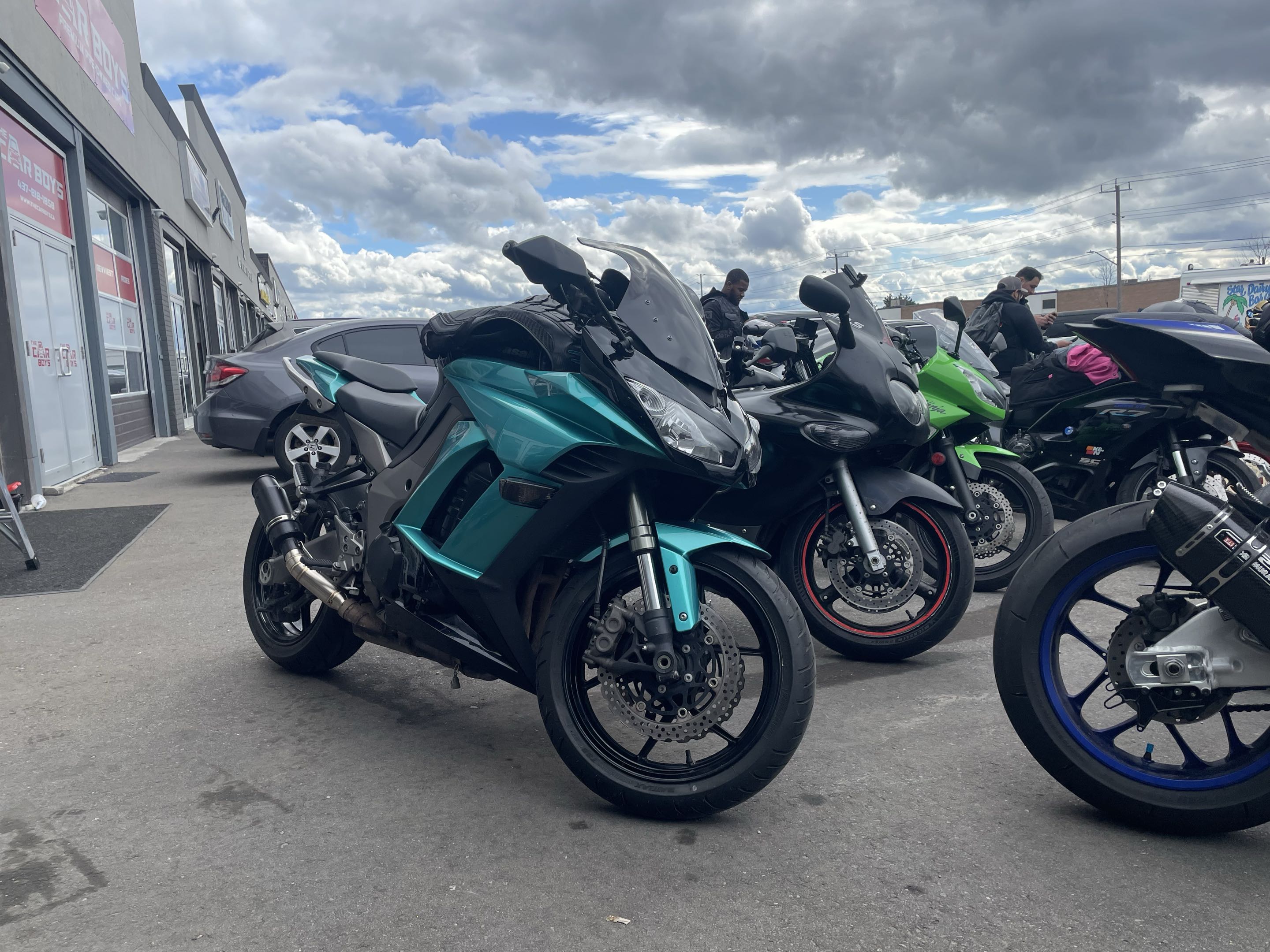Teal Kawasaki Ninja leading a row of motorcycles at a meetup